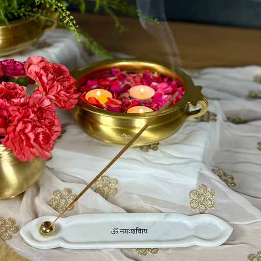 Decorative setting with flowers, candles, and an incense stick on a textured surface.