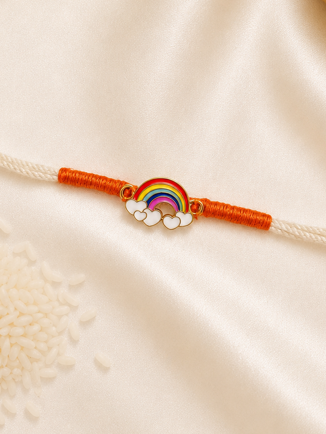 Kids Rainbow Rakhi with colorful rainbow and cloud enamel charm on a white thread with orange accents on a silk background.