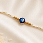 Blue evil eye Rakhi on a white braided thread with gold accents, displayed on a silk background.