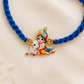 Kids Baby Krishna bracelet rakhi with adjustable blue braided cord and colorful enamel Krishna charm on a silk background.