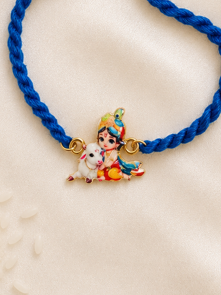 Kids Baby Krishna bracelet rakhi with adjustable blue braided cord and colorful enamel Krishna charm on a silk background.