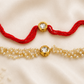Bhai-Bhabhi Rakhi Set with a gold-tone Kundan rakhi on a red thread and a matching pearl bracelet for Bhabhi, displayed on a silk background.