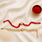 Bhai-Bhabhi Rakhi Set with a gold-tone Kundan rakhi on a red thread and a matching pearl bracelet for Bhabhi, displayed on a silk background with kumkum and rice.