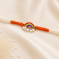 Kids Rainbow Rakhi with colorful rainbow and cloud enamel charm on a white thread with orange accents on a silk background.